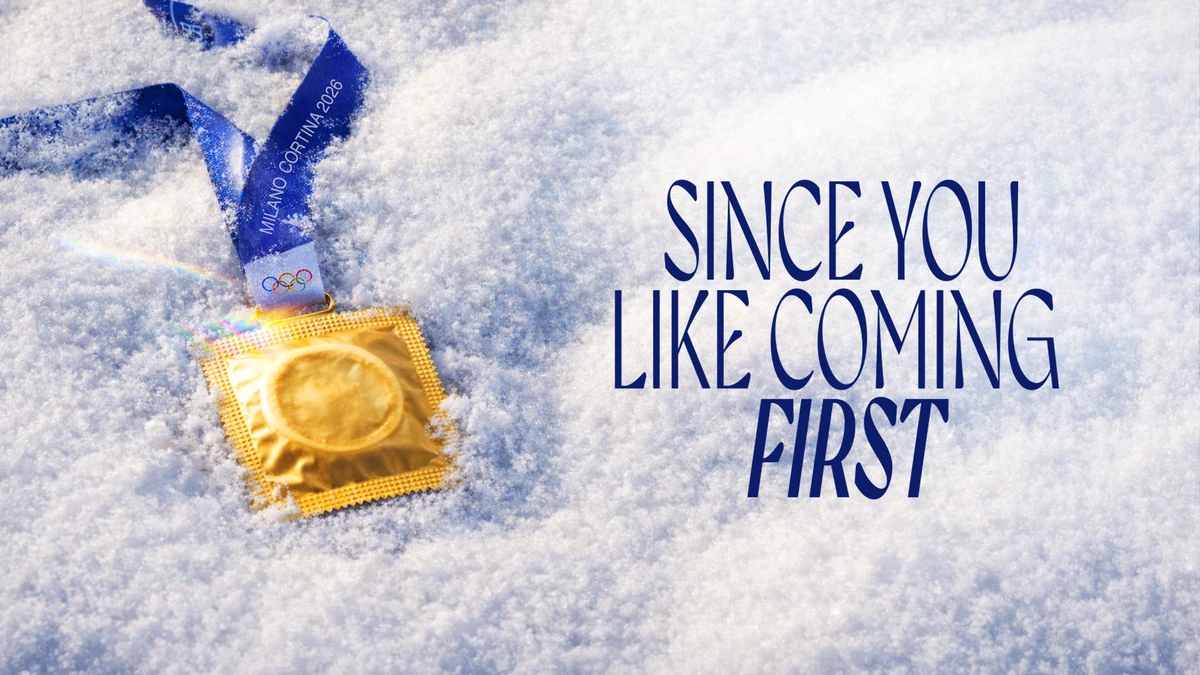 Gold: a condom wrapper hung on a Milano Cortina 2026 medal ribbon, lying in snow, headlined &ldquo;Since you like coming first.&rdquo;