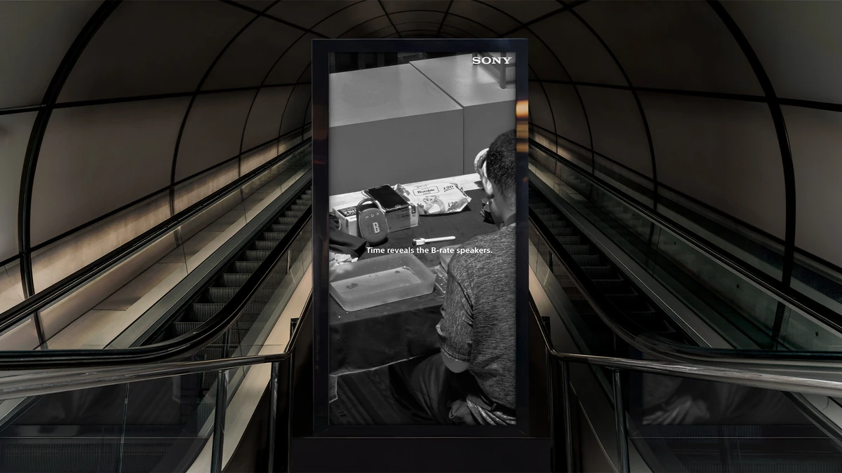 Digital out-of-home placement at the top of an escalator, showing the desk execution.